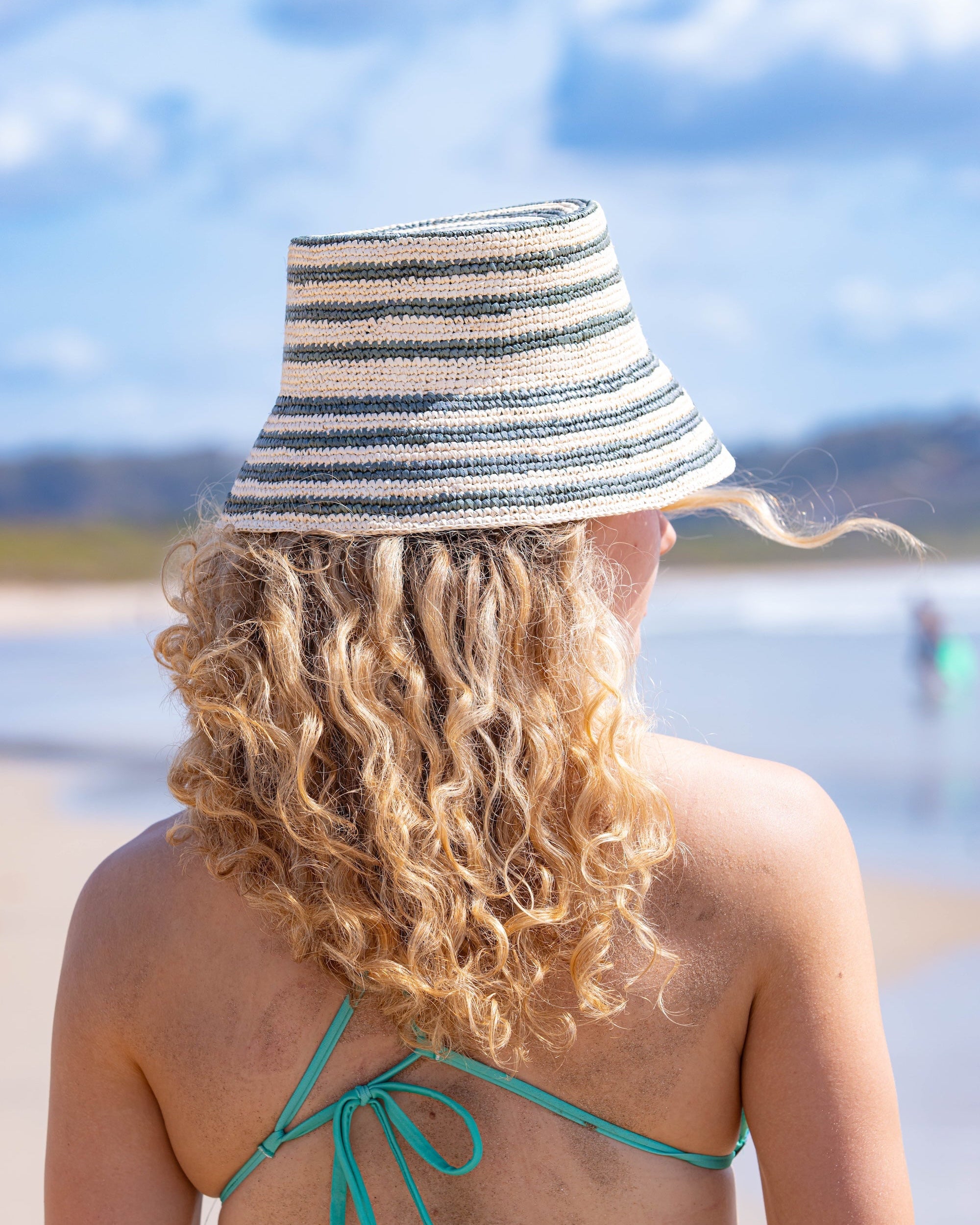 Woman wearing a striped straw bucket hat on a beach