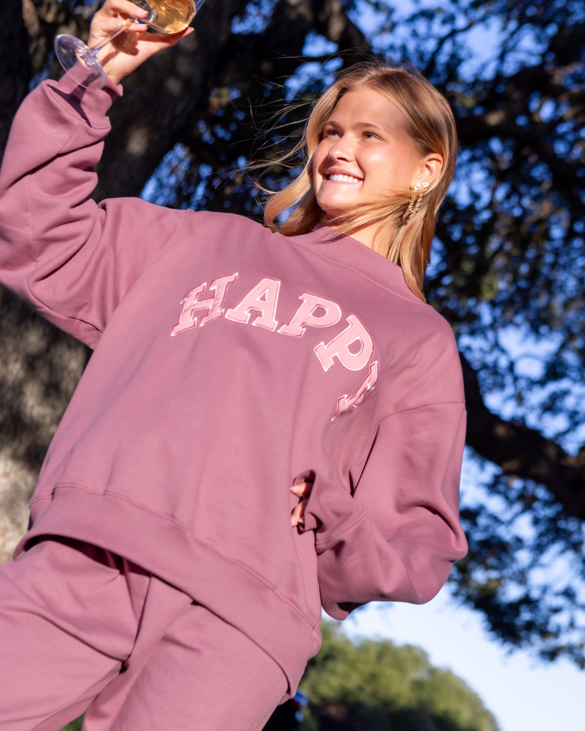 Person wearing a 'Happy' matching sweat set in mauve with pink letters
